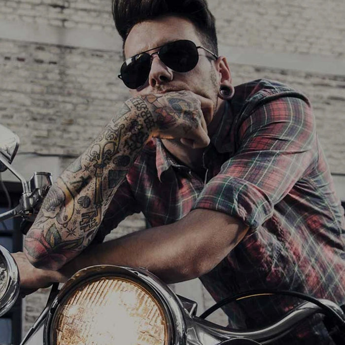 Tattooed man straddling a motorbike
